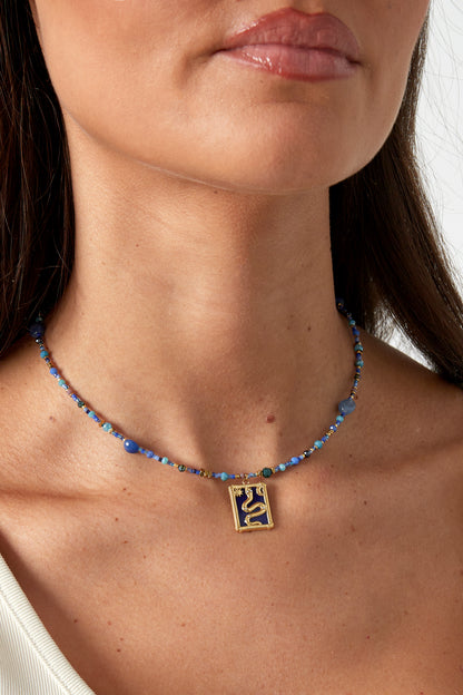 Model wearing the blue beaded snake necklace showing the pendant resting at the clavicle