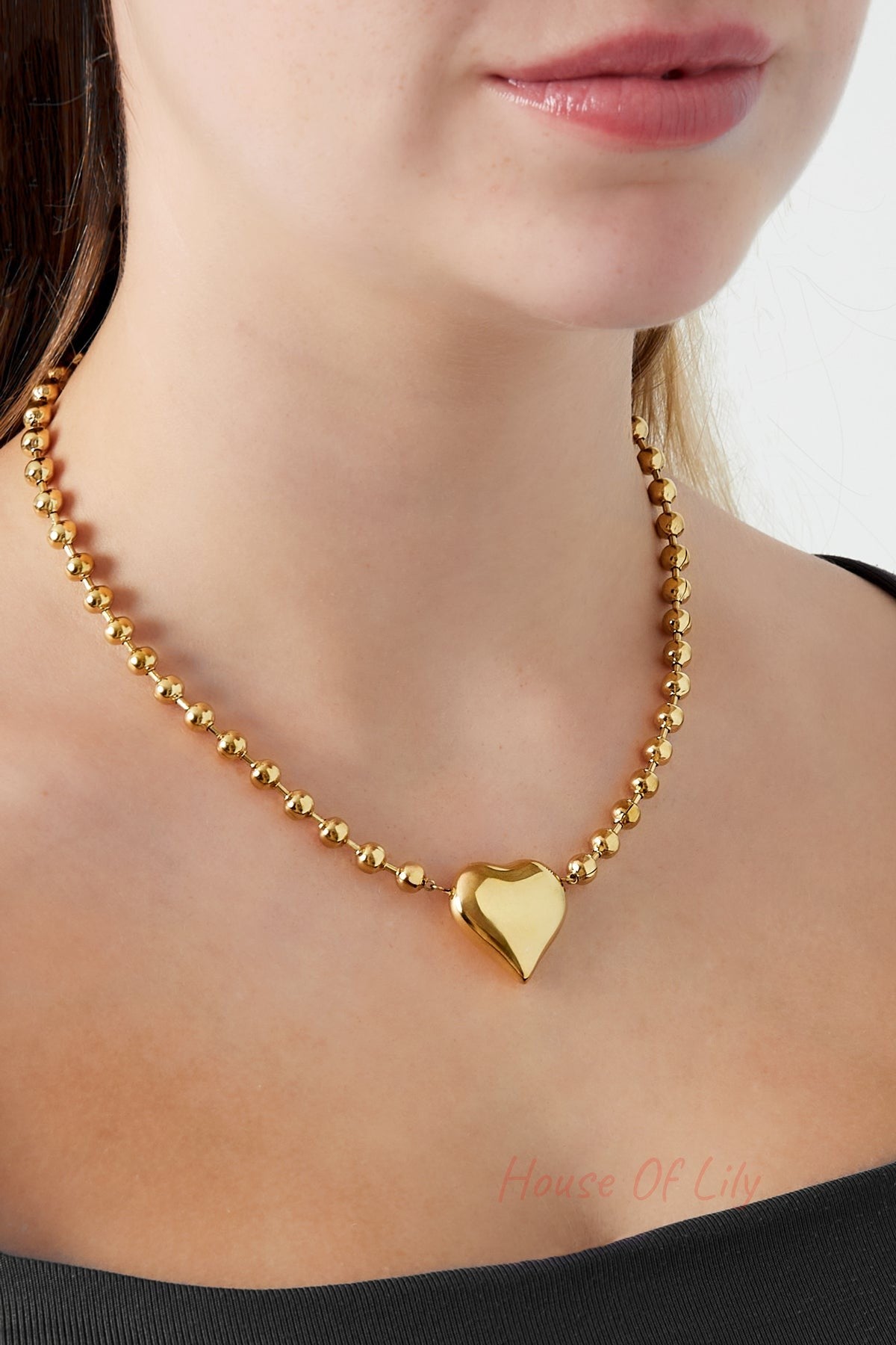 Woman wearing the golden beaded heart necklace styled with a black top