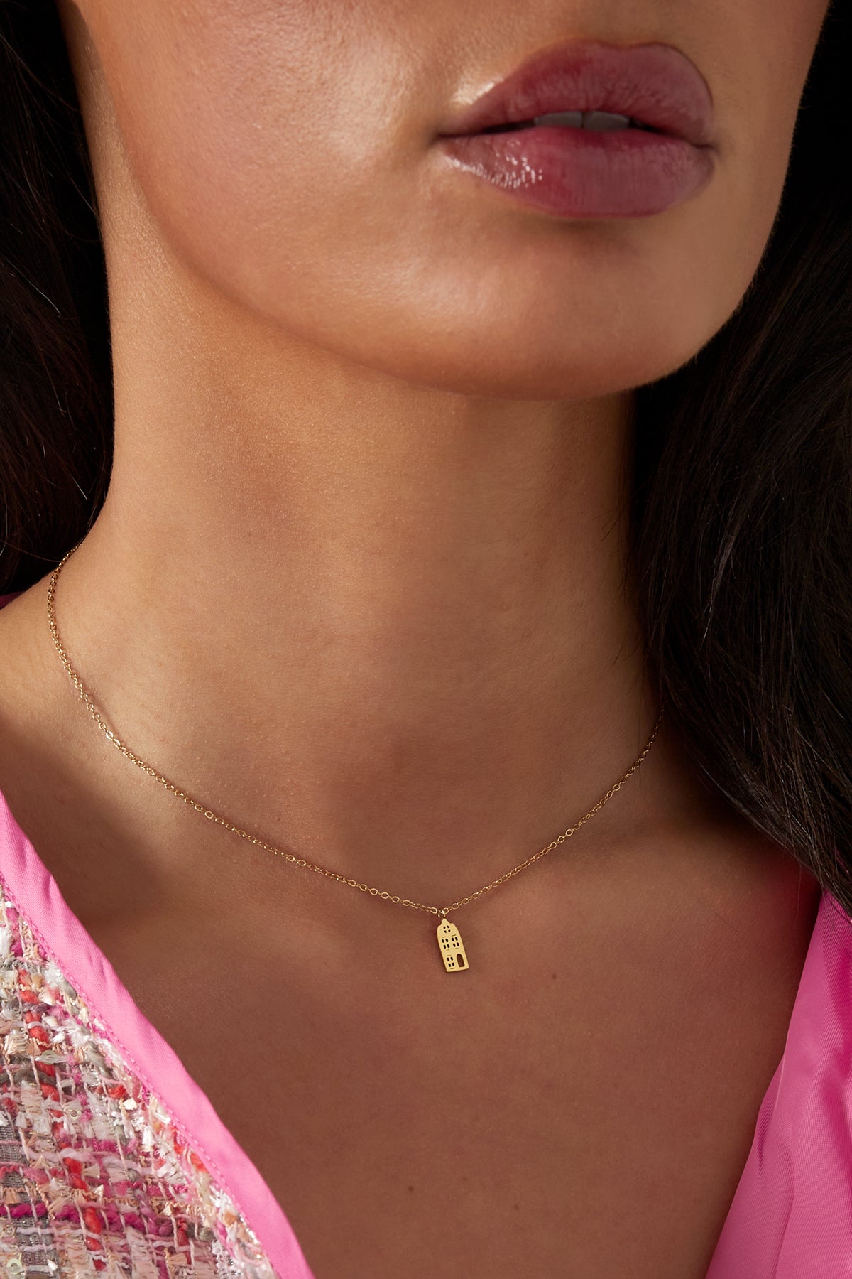 Model wearing the gold cityscape pendant necklace, styled with a pink and multicolour outfit showing neckline detail