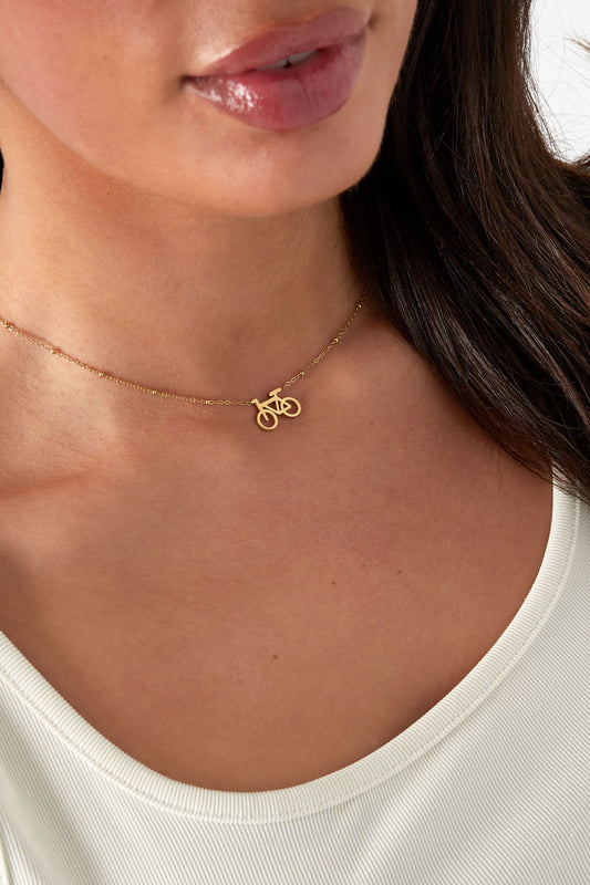 Model wearing the gold cycle chic pendant necklace paired with a white top