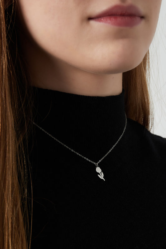 Close-up of a woman wearing a silver-tone tulip pendant necklace over a black top