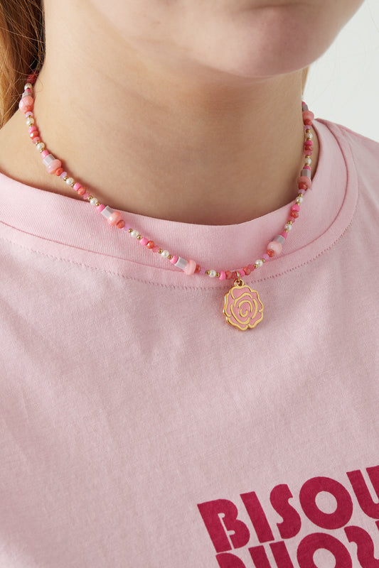 Model wearing a pink beaded rose necklace paired with a pink graphic tee