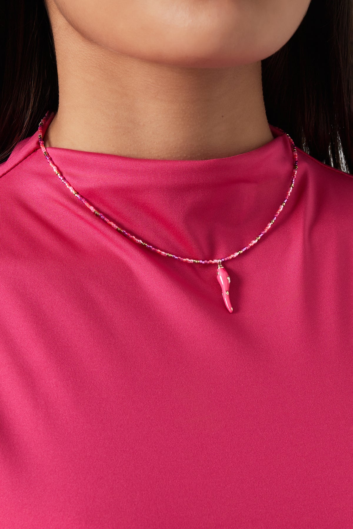 Model wearing vibrant pink beaded choker necklace with chili pepper star pendant, paired with matching pink top