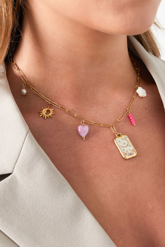 Model wearing the gold-toned charm necklace showing charms close-up, styled with a light blazer