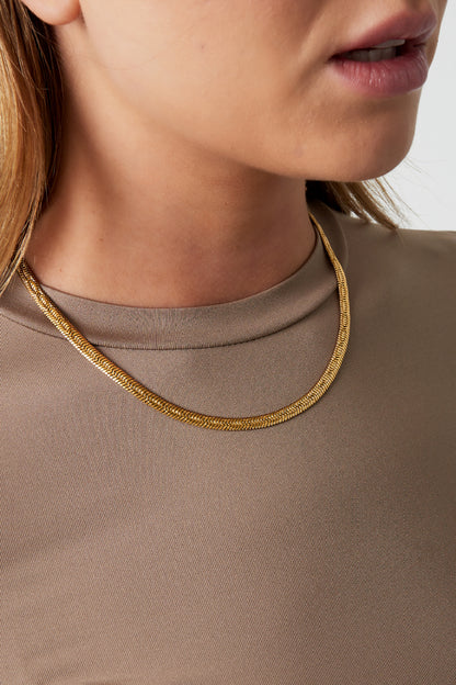 Model wearing a short gold herringbone chain necklace styled with a taupe brown shirt