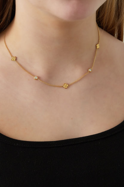 Close-up of a woman wearing the gold-tone clover chain necklace with rhinestone details styled with a black top