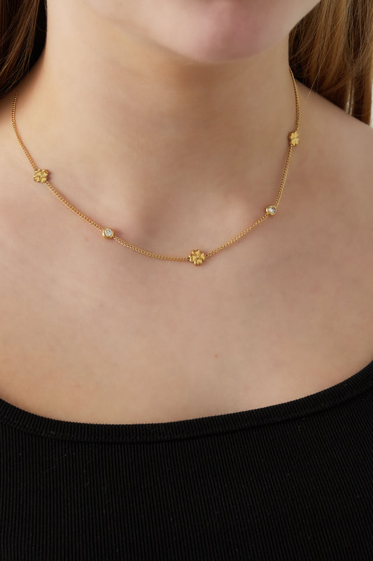 Close-up of a woman wearing the gold-tone clover chain necklace with rhinestone details styled with a black top