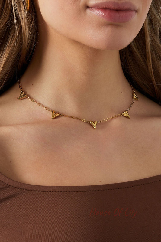 Model wearing the gold-tone heart link chain necklace paired with a brown top, showcasing the necklace resting elegantly on the neckline
