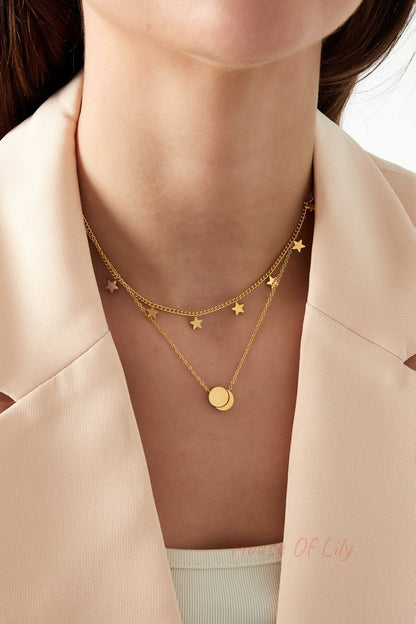 Close-up of a woman wearing a gold layered star charm necklace with round pendant and beige blazer