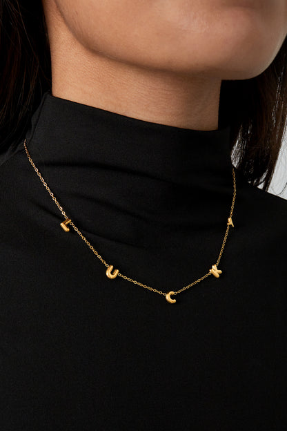Model wearing gold LUCKY letter pendant necklace with black turtleneck