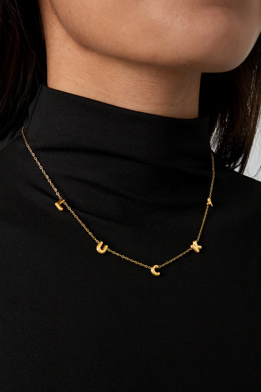 Model wearing gold LUCKY letter pendant necklace with black turtleneck