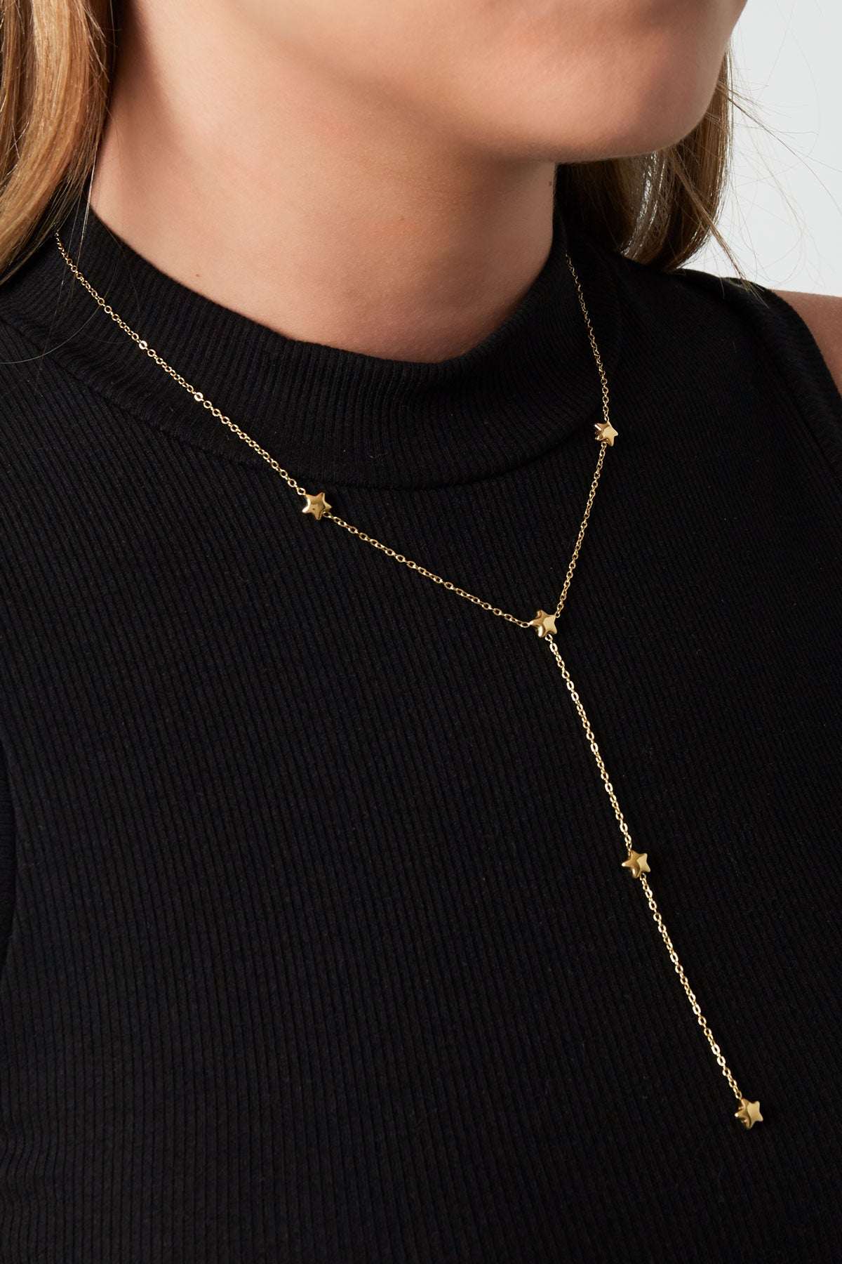 Model wearing gold star charm lariat necklace with black ribbed sleeveless top