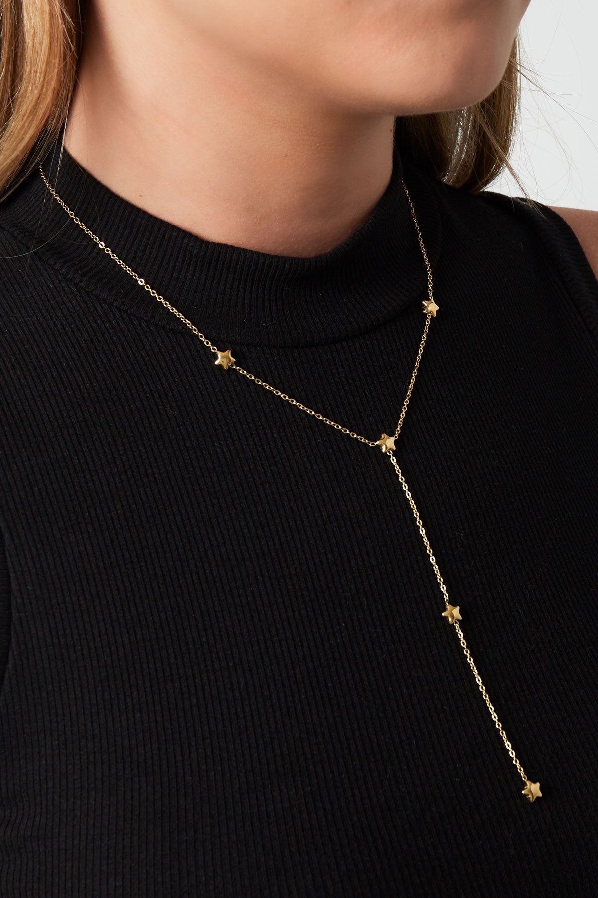 Model wearing gold star charm lariat necklace with black ribbed sleeveless top