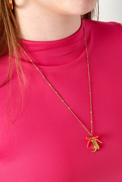 Woman wearing gold-tone cowboy boot pendant necklace featuring bright pink and orange beads with pink top