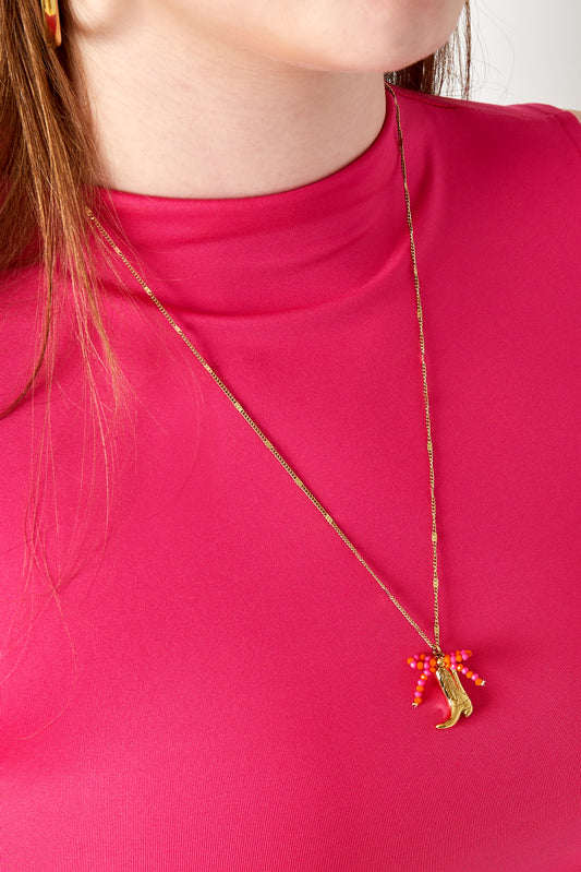 Woman wearing gold-tone cowboy boot pendant necklace featuring bright pink and orange beads with pink top