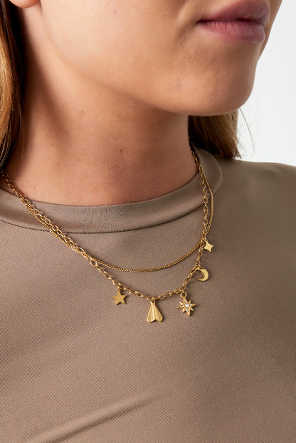 Close-up of a woman wearing the gold layered celestial charm necklace paired with a taupe top