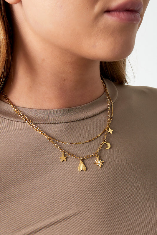 Close-up of a woman wearing the gold layered celestial charm necklace paired with a taupe top