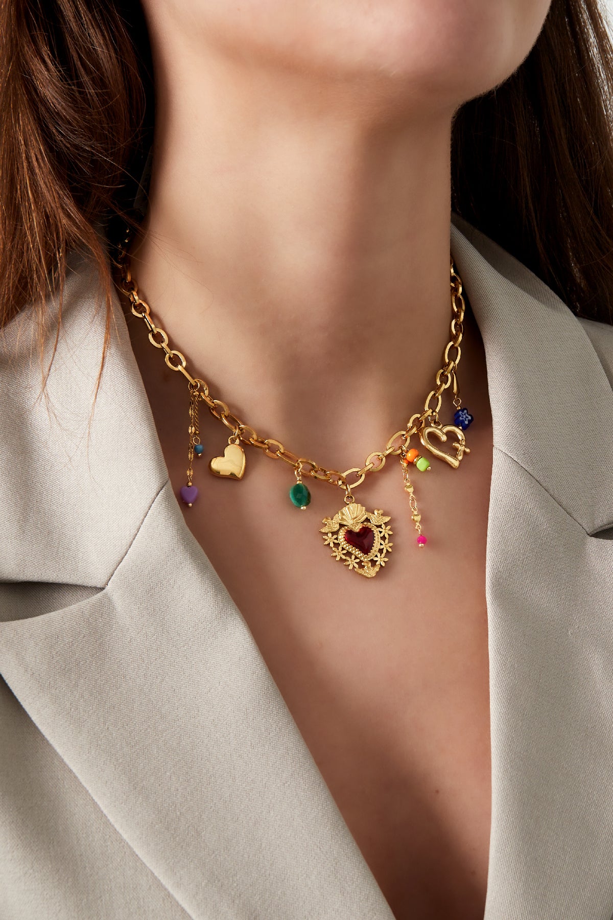 Model wearing the gold-tone charm necklace paired with a neutral blazer highlighting the layered colourful and heart charms