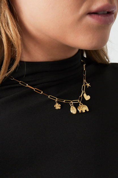Model wearing the golden charm link necklace paired with a black top, highlighting delicate and detailed charms