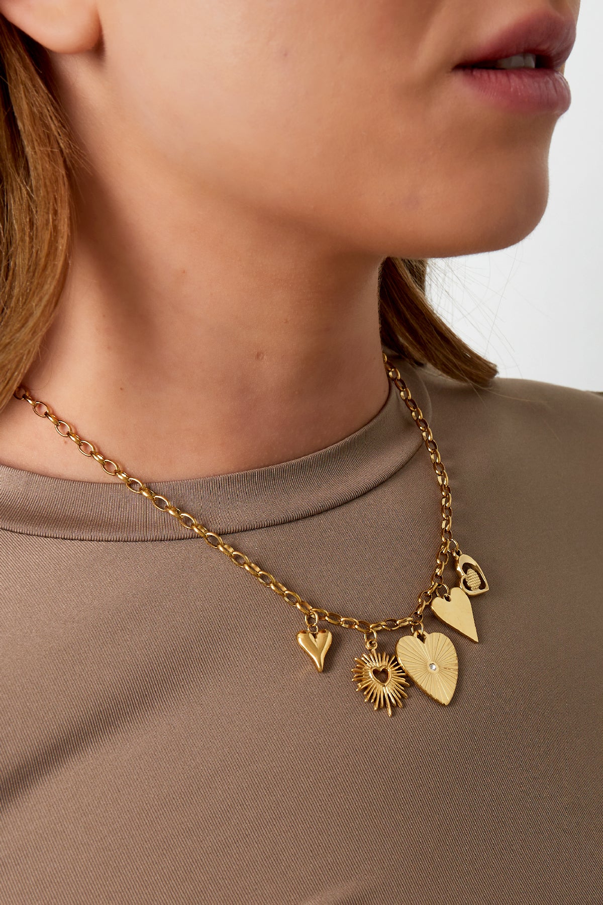 Model showcasing the gold link necklace with distinctive charms over a beige top