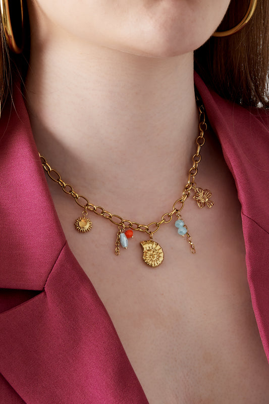 Model wearing gold charm necklace paired with bold pink blazer
