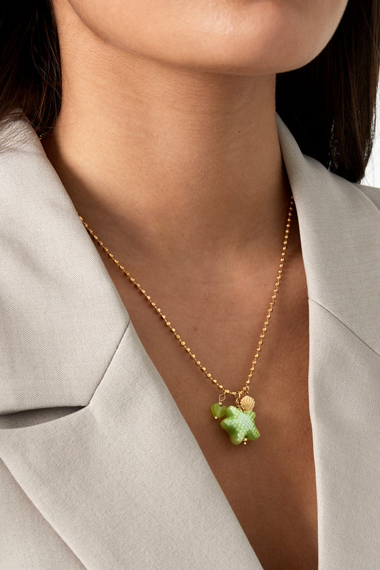 Model wearing the gold-tone starfish charm necklace paired with a light beige blazer, showing the necklace close to the neckline