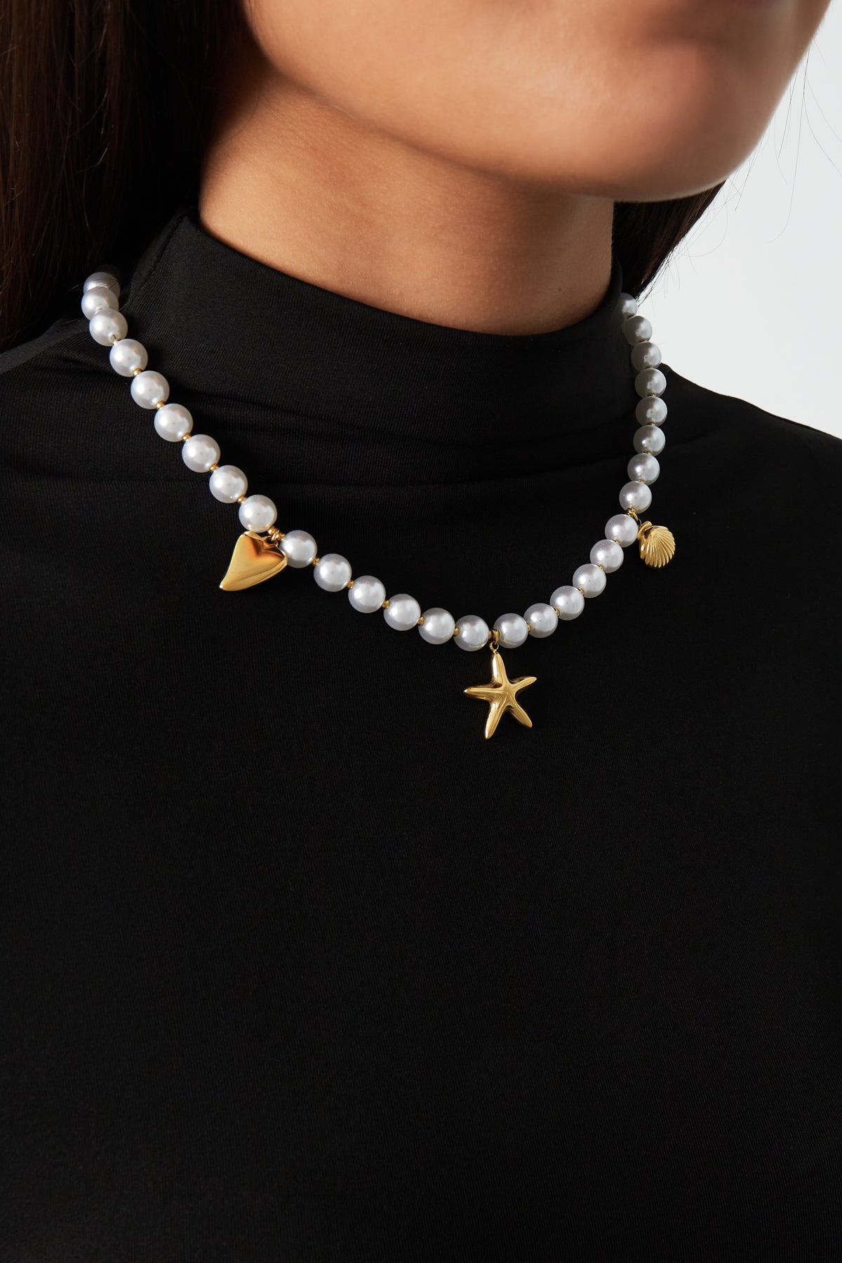 Woman wearing pearl charm necklace paired with black top showcasing the necklace's elegant design