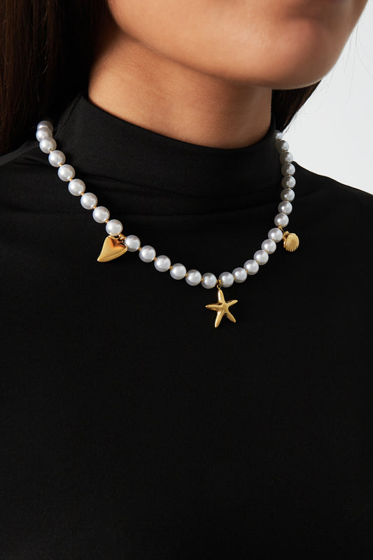Woman wearing pearl charm necklace paired with black top showcasing the necklace's elegant design
