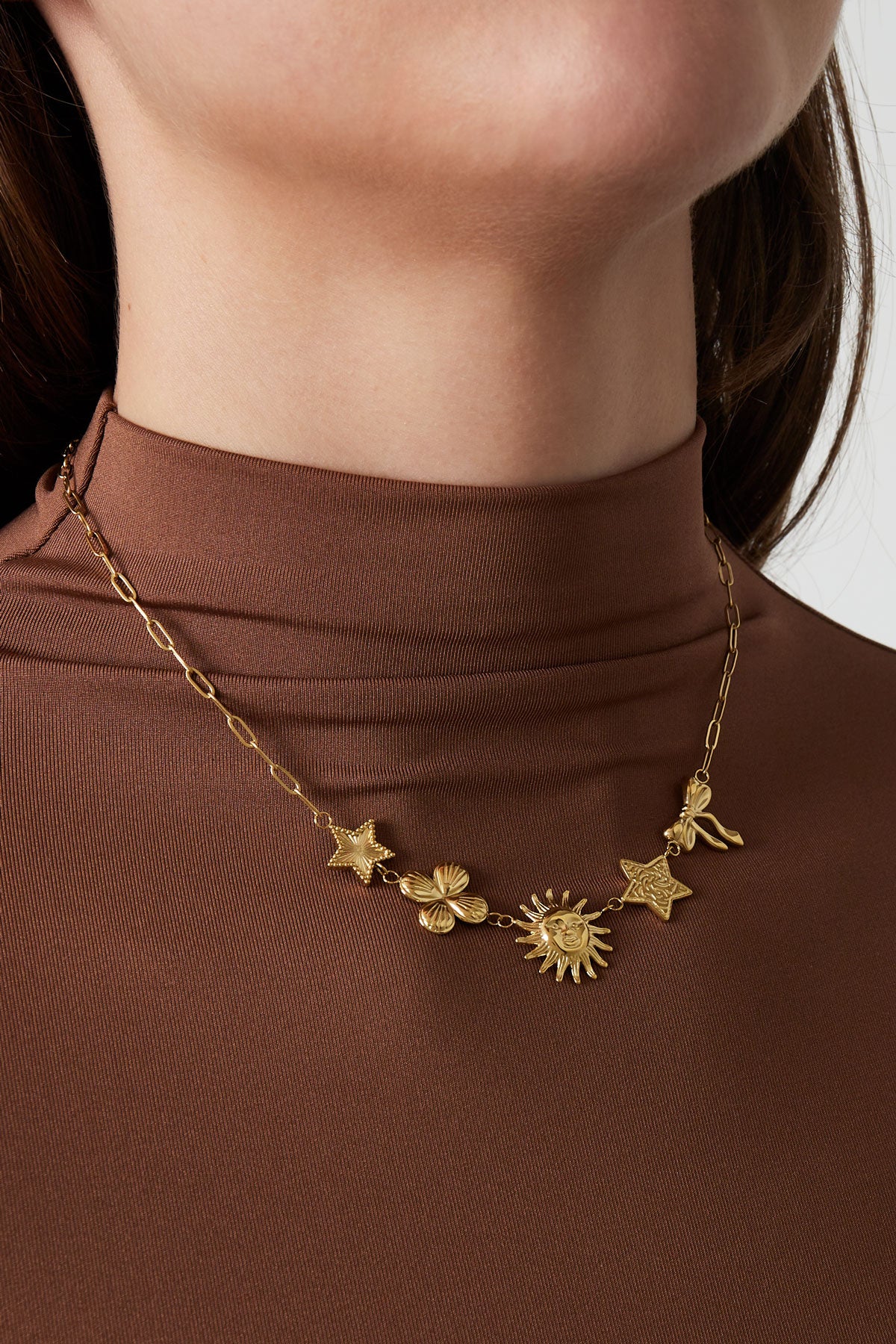 Model wearing the gold-tone celestial charm necklace with brown high-neck top, close-up on neck and collarbone