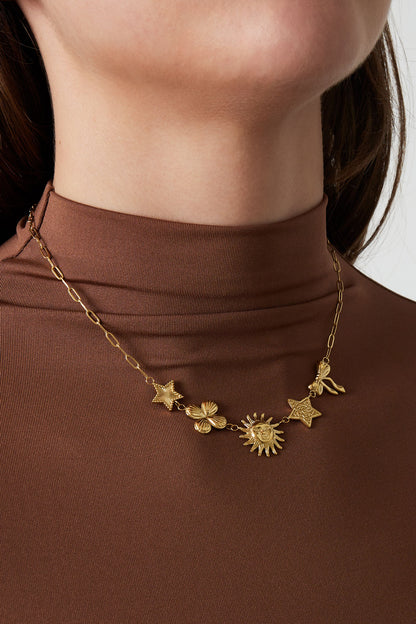 Model wearing the gold-tone celestial charm necklace with brown high-neck top, close-up on neck and collarbone