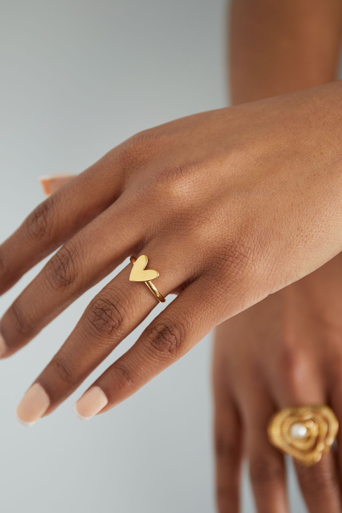Close-up of a woman's hand wearing the gold-tone heart ring with polished nails