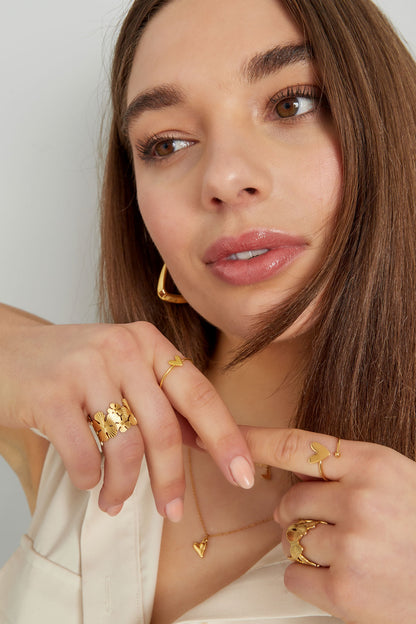 Close-up portrait of woman wearing the gold heart minimalist ring with matching gold jewelry