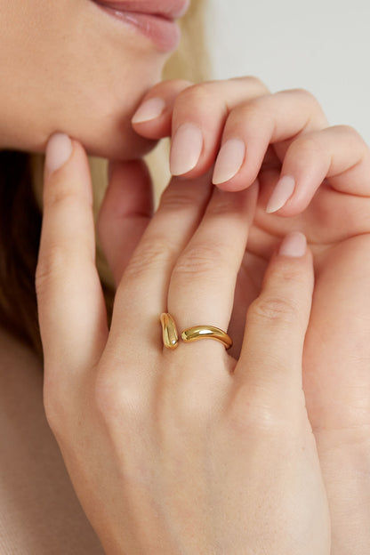 Close-up of a woman's hand wearing a gold twist open ring with a minimalist twisted design