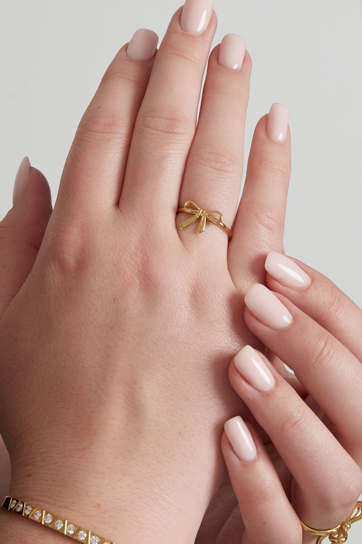 Gold bow accent ring worn on a woman's finger with neatly manicured nails