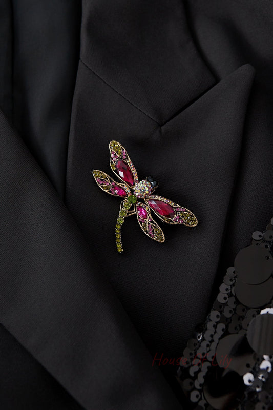 Dragonfly brooch pinned on black fabric jacket, showcasing its vibrant pink, red, and green stones