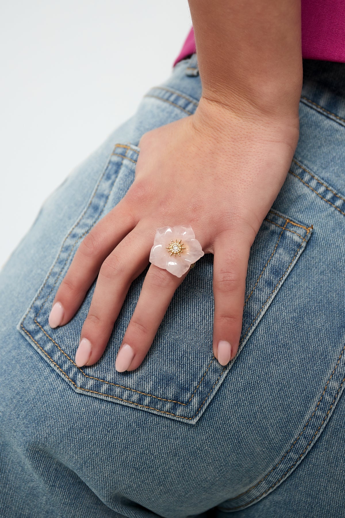 Woman wearing pink floral statement ring on finger paired with denim jeans