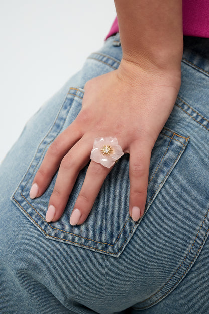 Woman wearing pink floral statement ring on finger paired with denim jeans