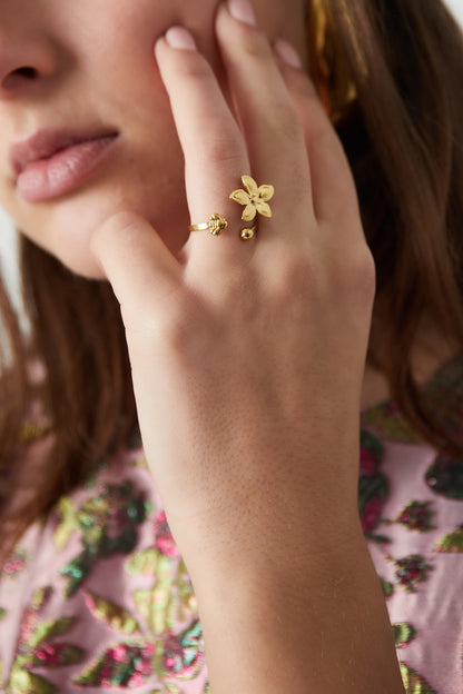 Close-up of a woman wearing a gold floral statement ring on her finger, showcasing the design