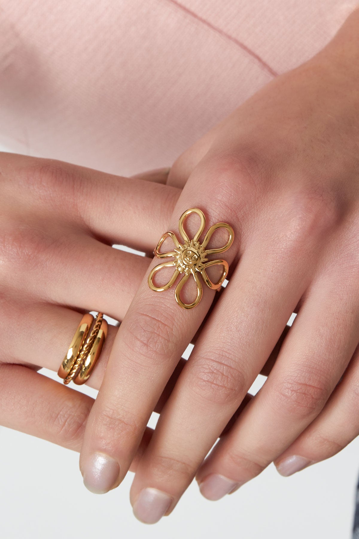 Close-up of a woman’s hand wearing the gold-tone Sunshine Statement Ring on the middle finger paired with two other gold rings
