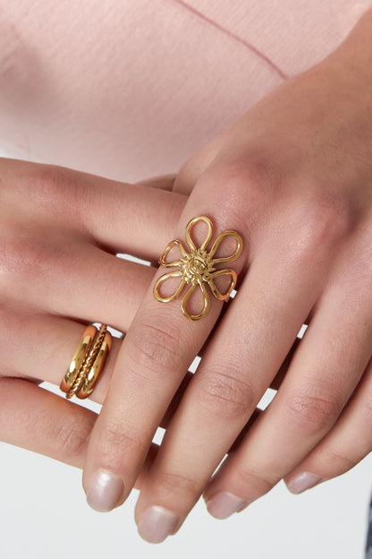 Close-up of a woman’s hand wearing the gold-tone Sunshine Statement Ring on the middle finger paired with two other gold rings