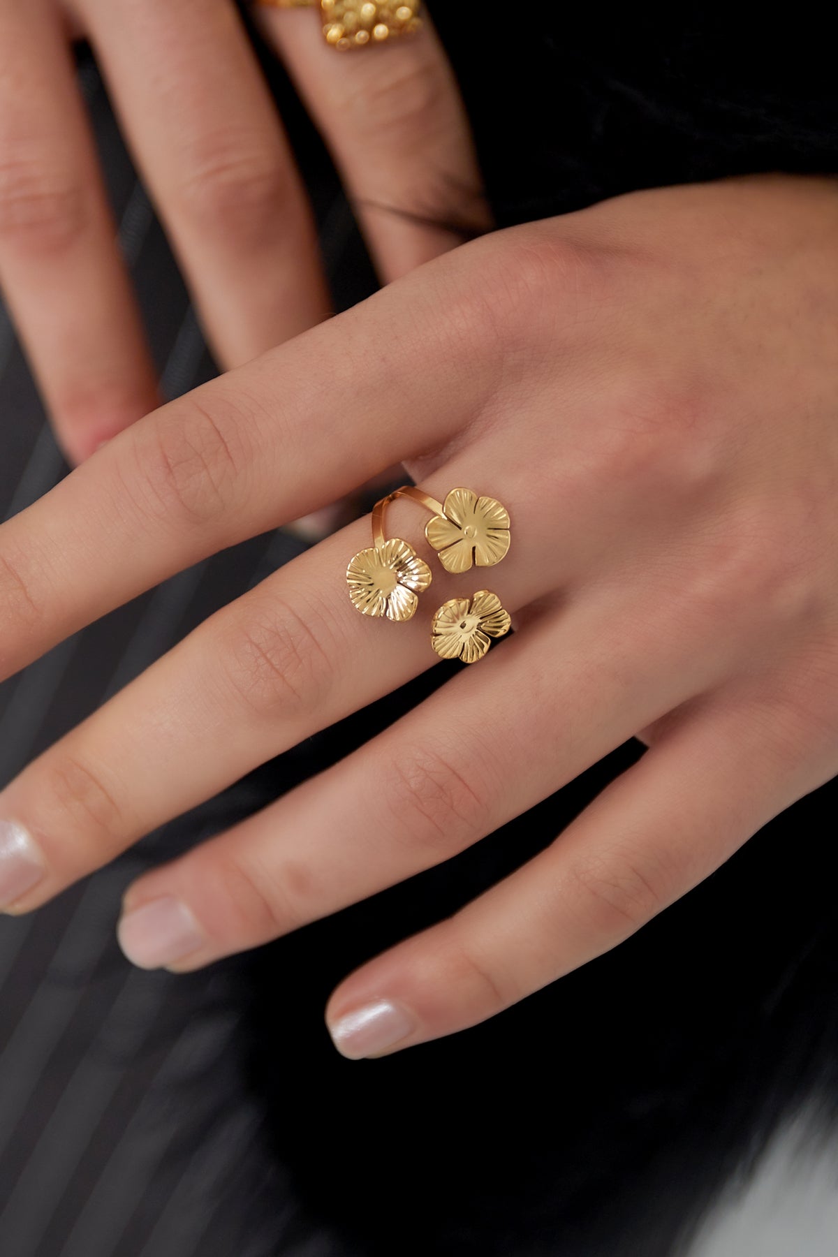 Close-up of hand wearing adjustable gold floral trio statement ring with three flowers