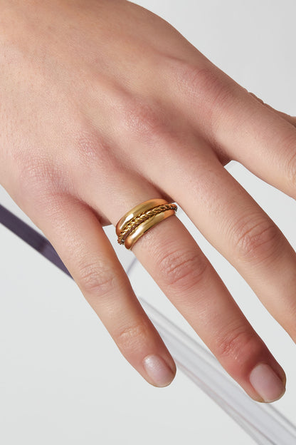 Close-up of a woman's hand wearing a gold layered spiral statement ring showing twisted detail