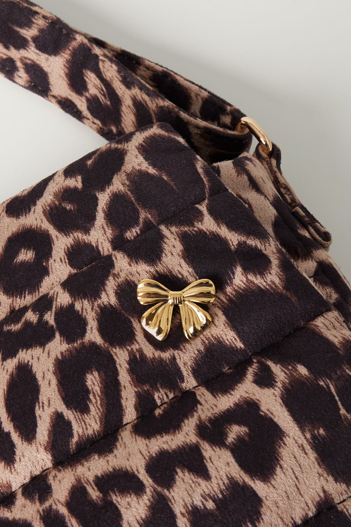 Gold bow brooch pinned to leopard print fabric bag showing size and style