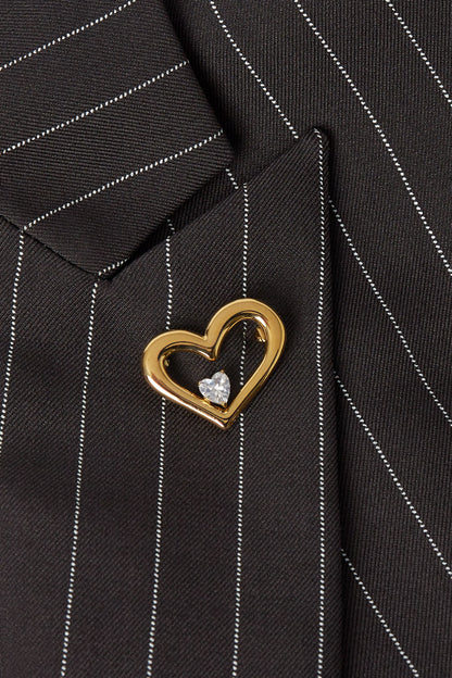 Gold heart-shaped brooch pinned on black pinstripe suit lapel close-up