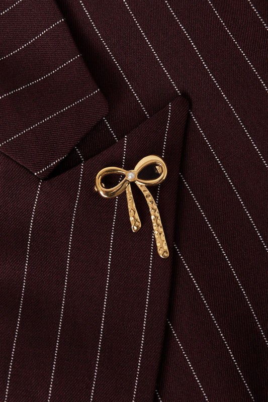 Gold hammered bow brooch pinned on burgundy pinstripe blazer lapel