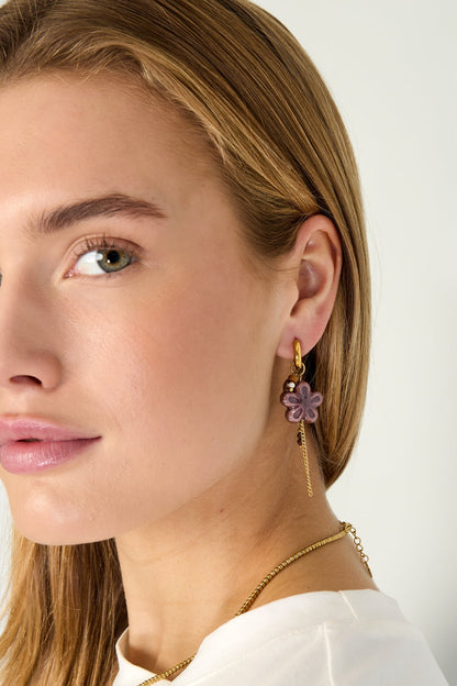 Front angle of a woman wearing brown resin flower hoop earrings with gold chain tassels, showing the playful and aesthetic style