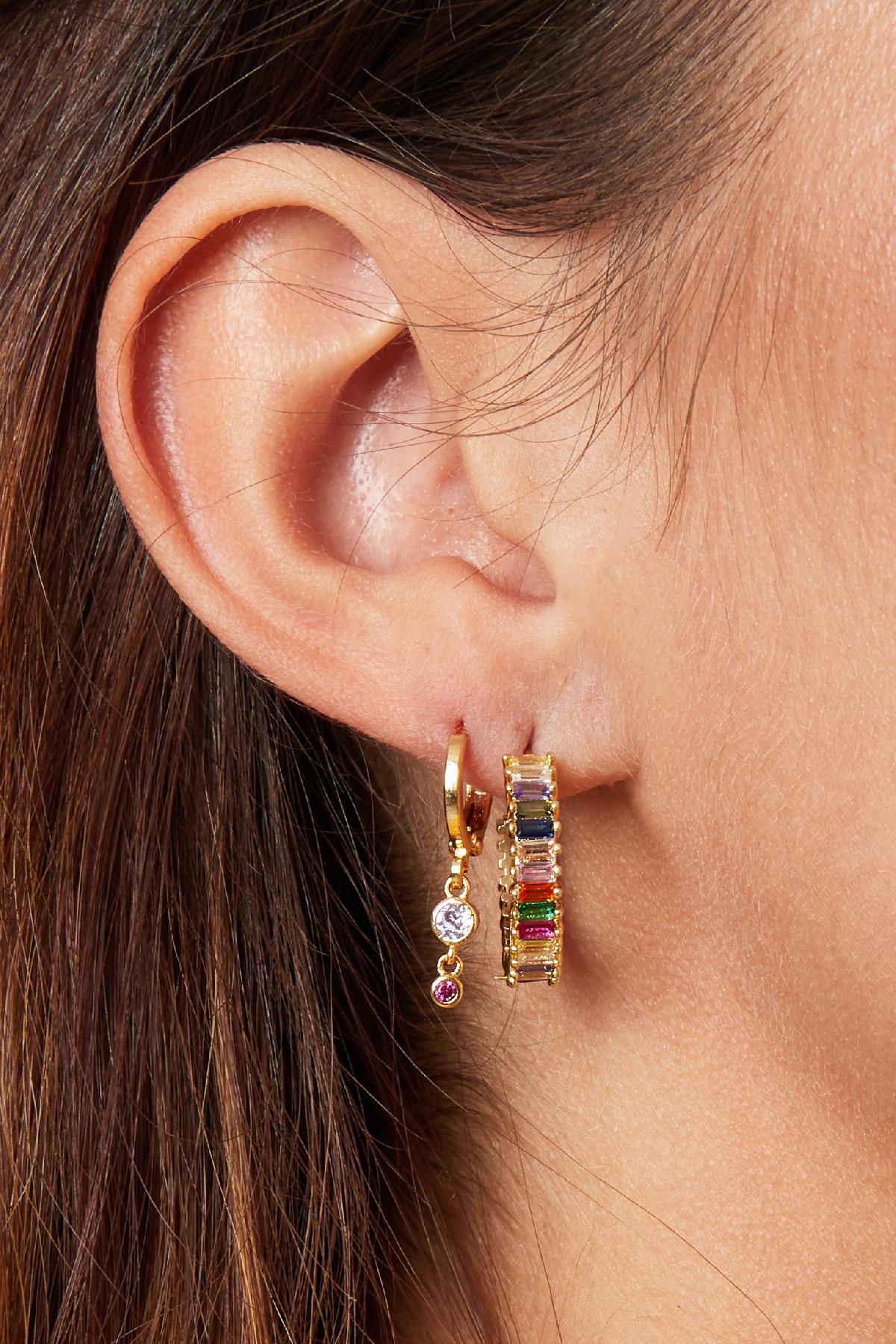 Close-up of an ear wearing colorful baguette rhinestone hoop earring alongside a small gold dangle earring