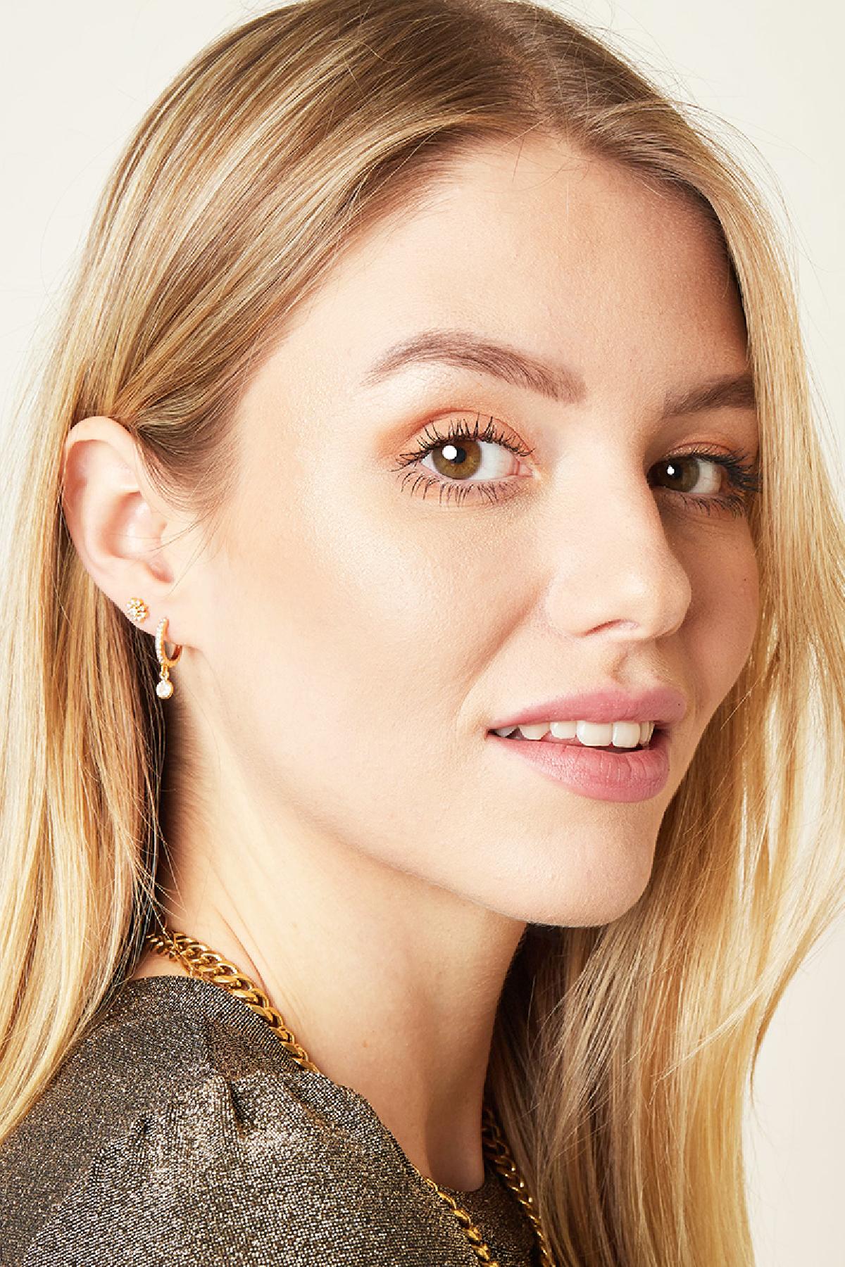 Portrait of a smiling woman with blonde hair wearing the gold crystal flower piercing earring alongside a stylish gold chain necklace