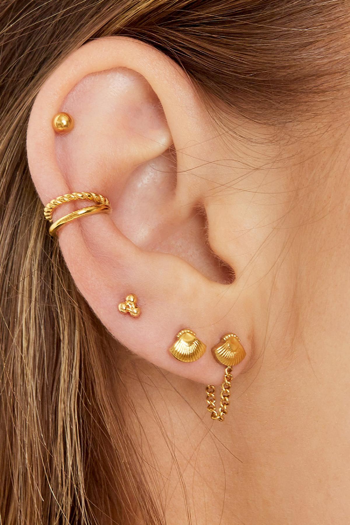 Model wearing gold double ear cuff and multiple gold earrings featuring shells and studs