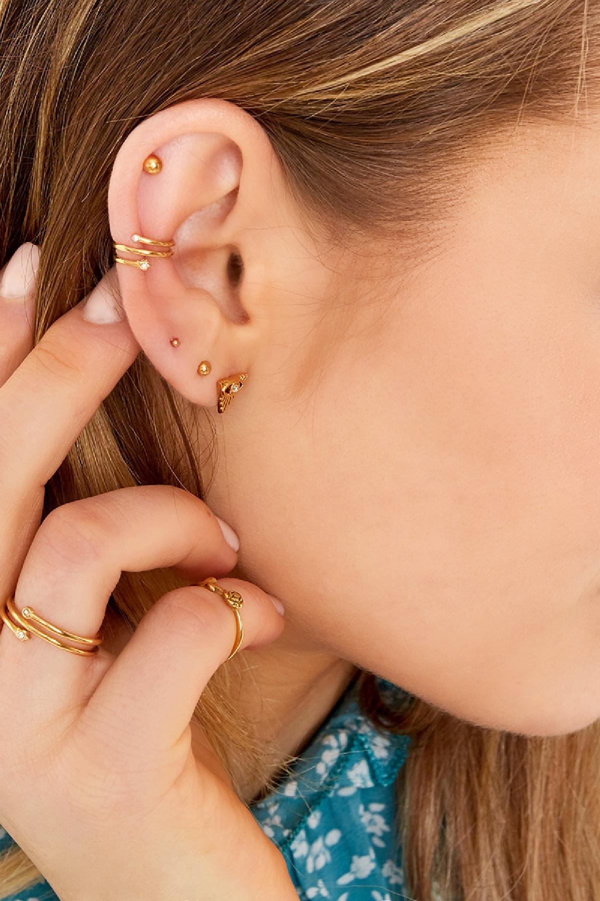 Side view of model wearing gold spiral earcuff with zircon stones, styled with multiple gold earrings and rings